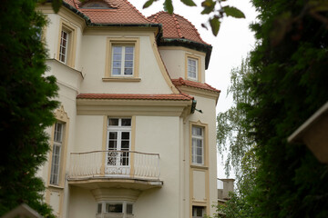 A large and spacious white house that features a lovely balcony and is topped with a charming red tile roof