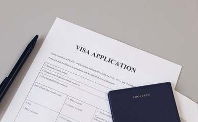Visa application form, pen  and passport on desk.