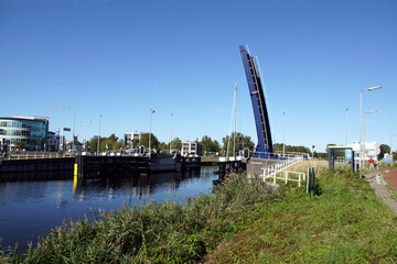 Fototapeta premium Open bicycle - pedestrian drawbridge Vlielandbrug over the canal (Noordhollandsch Kanaal) in the Dutch city of Alkmaar. Blue sky, autumn, October, Netherlands