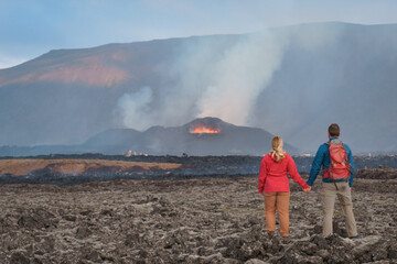 A hiking couple is observing the eruption of Sundhnúkagígar volcano in Iceland's Skógfellahraun...