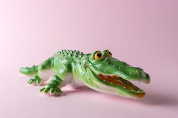 Green crocodile toy on pastel pink background. Minimal art concept.