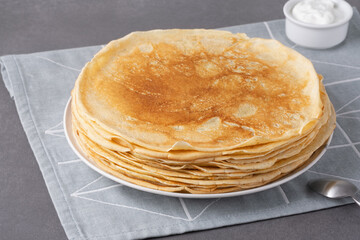 Stack of traditional russian pancakes blini on gray background. Homemade russian thin pancakes...