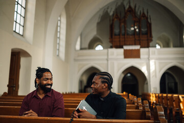 Priest holding bible talking to man in church