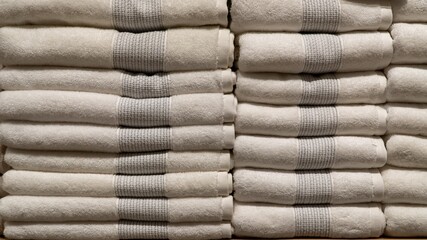 A stack of neatly folded, same-colored towels sits on a shelf in a home decor store. The towels create a clean, organized, and textured display.