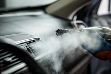 Steam cleaning the interior of a car to remove dirt and allergens at an auto detailing shop in the...