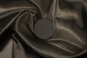 Circle canvas paper frame on brown black silk fabric background. Abstract copy space texture.