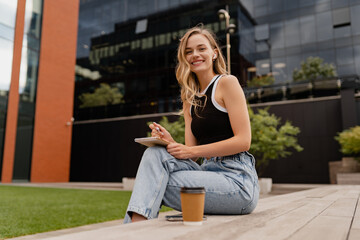 young pretty woman sitting in student campus co-working outside