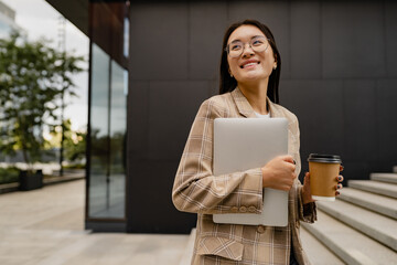 young pretty asian woman walking outside in street doing business