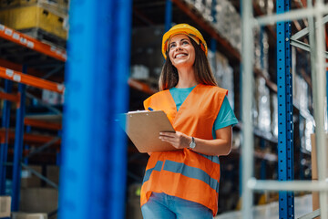 Female warehouse worker checking inventory and smiling