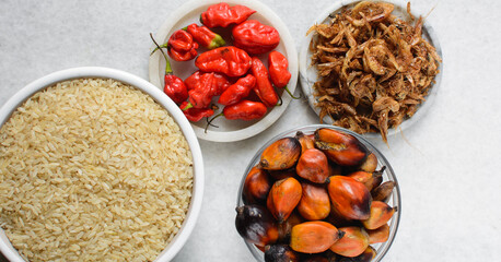 mise en place of ingredients of nigerian banga rice, process of making palm nut rice, top view of rice, palm nut,crayfish and pepper on a table