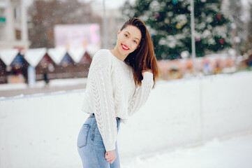 Young girl in a white sweater standing in a winter park