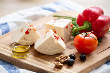 Homemade organic white cheese served with Tomatoes, dill, crispy bread, walnut and olive oil on wooden board on the table. Healthy food, snack and eating.
