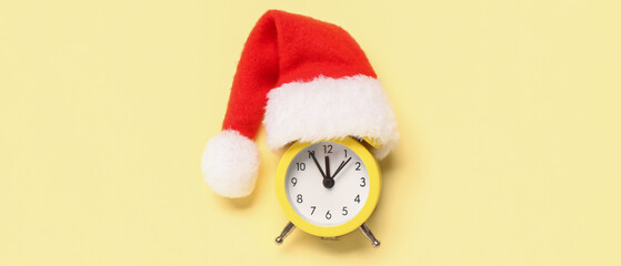 Alarm clock with Santa hat on beige background