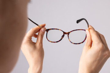 Poor vision concept, woman with poor vision holding glasses in front of her