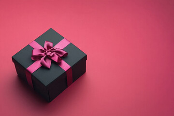 Fototapeta premium A black box with a pink bow on top of it. The box is sitting on a pink background