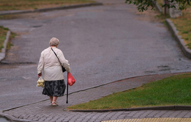 an elderly woman carries bags of apples