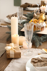 Christmas setting with burning candles on dining table in kitchen, closeup