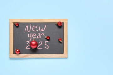 Blackboard with text HAPPY YEAR 2024 and red balls on blue background