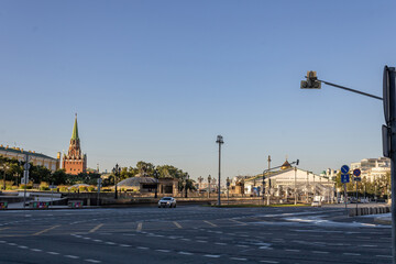 Obraz premium Street in the center of Moscow. A car is driving. Lanterns, traffic lights, road signs. Cloudless sky. The Kremlin in the background. Early morning.