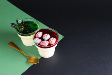Plastic cups with delicious panna cotta and spoon for Halloween celebration on color background