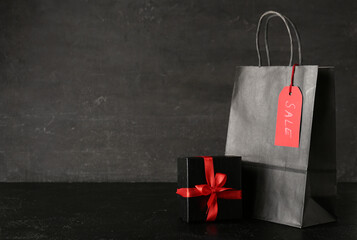 Shopping bag and gift box on dark grunge table. Black Friday sale