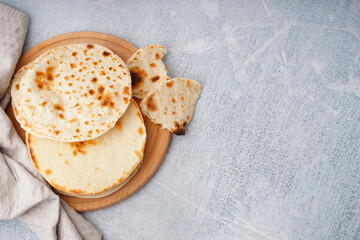 Wooden board of tasty pita bread on white background