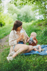 Mother's time with her little son. A young mother is sitting on the grass in the park. A walk of a mother with her son.