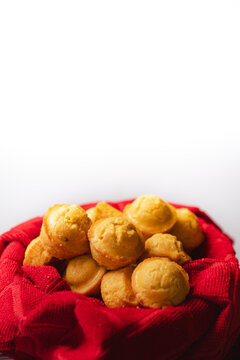 tiny cornbread muffins in a red towel-lined basket in front of a white background