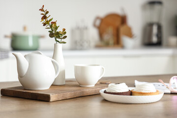 Modern breakfast setup with coffee, fresh pastries and eucalyptus branches in vase on wooden table, closeup