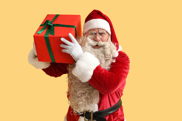 Santa Claus with Christmas gift on yellow background