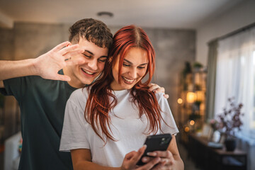 Welcoming young couple waving during video call on mobile phone