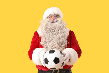 Santa Claus with soccer ball on yellow background