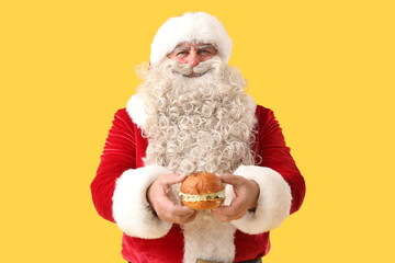 Santa Claus with tasty burger on yellow background