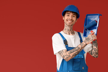 Male painter with roller and tray on color background