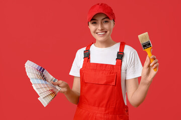 Female painter with color palettes and paintbrush on red background