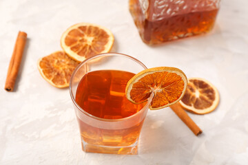 Glass of delicious Old Fashioned Cocktail with dried orange slices and cinnamon sticks on white...