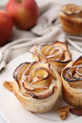 Freshly baked apple roses and walnuts on table, closeup. Puff pastry