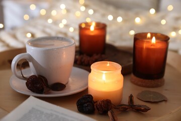 Burning candles, coffee and decor on tray, closeup. Autumn atmosphere