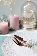 Christmas place setting with plate, cutlery and festive decor on table, closeup