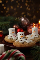 Funny marshmallow snowmen, cookies and festive decor on table