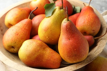 Ripe juicy pears in bowl on table, closeup