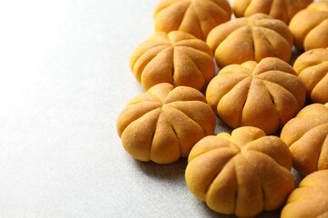 Tasty pumpkin shaped buns on light table, closeup. Space for text