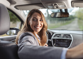 young woman looking at back over shoulder while driving car