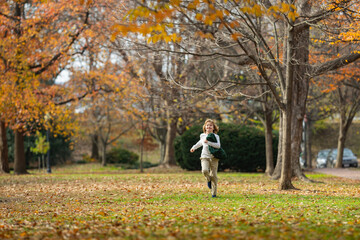 Fototapeta premium Autumn Baby Portrait In Fall Yellow Leaves. Little Child play in Park Outdoor. Autumn Clothing for warm October Season. Autumnal mood. Little child boy in autumn orange leaves, outdoor.