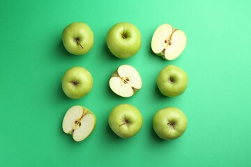 Flat lay composition with whole and cut apples on green background