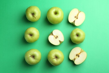 Flat lay composition with whole and cut apples on green background