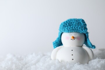 Cute decorative snowman on artificial snow against light background. Space for text