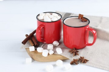 Yummy cocoa with marshmallows and spices on white wooden table