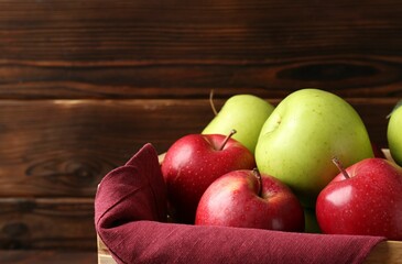 Ripe red and green apples in crate against wooden background, closeup