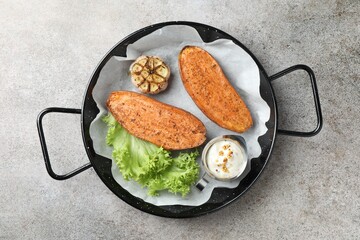 Tasty cooked sweet potato served in baking dish on grey textured table, top view